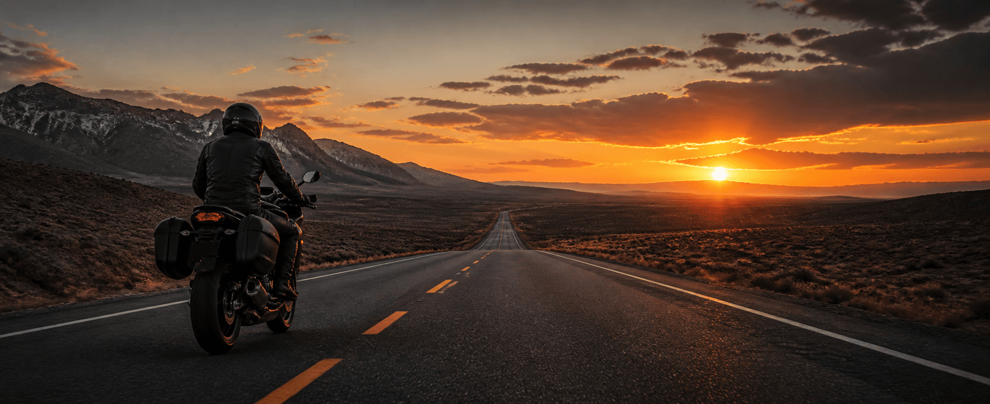 Motorcyclist riding on an open road at sunset